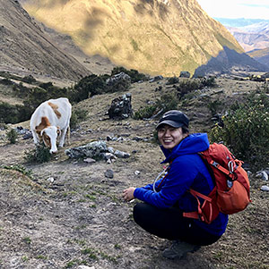 Jisoo Hong smiling on hillside with cow