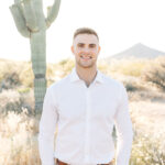 Tim smiles at camera with cactus in the background.